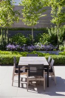 Table à manger et chaises d'extérieur grises sur une terrasse pavée contemporaine
