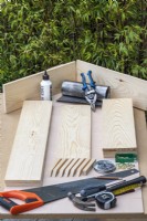 Création étape par étape d'un théâtre végétal. Étape 1 : assembler les outils et les longueurs prédécoupées de bois raboté de 50 x 150 mm, le dos en contreplaqué marin et les supports d'étagère.