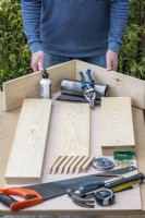 Création étape par étape d'un théâtre végétal. Étape 1 : assembler les outils et les longueurs prédécoupées de bois raboté de 50 x 150 mm, le dos en contreplaqué marin et les supports d'étagère.
