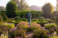 La statue de la Lampe de la Sagesse entourée de Sedum « Autumn Joy », d'Heliotropium arborscens et de topiaires Box and If dans le jardin à la française des Waterperry Gardens 