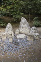 Groupe de bouddhas en pierre avec des pièces de monnaie au sol comme offrandes. 