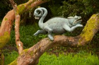 Une sculpture en bronze d'un caméléon par Alexander Jones sur une branche d'arbre. 