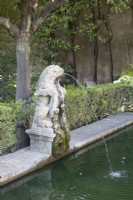 Une vieille sculpture de lion déverse de l'eau dans une piscine dans les jardins du palais du Real Alcazar, à Séville. Espagne. Septembre. 