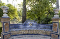 Un banc courbé et carrelé à carreaux avec des piliers aux extrémités et des urnes ornées placées sur les piliers. Jardins du véritable palais de l'Alcazar, Séville. Espagne. Septembre. 