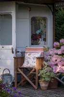 Chaise de jardin vintage à l'ancienne entourée de pots remplis de fleurs d'été 