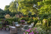 Petit jardin dans la cour, avec d'élégants meubles de jardin en métal et des plantations en pot de géraniums sous les arbres du jardin ombragés 