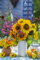 Couronne d'été et bouquets de tournesols, amarante, capucine, soucis en pot et tanaisie dans des vases sur la table. 