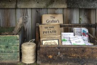 Boîtes en bois avec livres de jardinage vintage, sacs de graines et ficelle de jardinage placées sur une étagère 