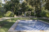 Une piscine carrelée bleu et blanc avec deux fontaines, une grande pergola incurvée est en arrière-plan. Parque de Maria Luisa, Séville, Espagne. Septembre 