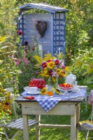 Bouquet d'été avec tournesols, Dahlia, Solidago, Agastache et Malva sur la table dressée pour un thé. 