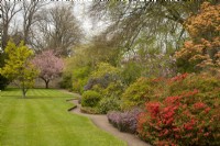 Un parterre de fleurs d'Acer, de Rhododendron, de Syringa, d'Erica et de Prunus le long d'un chemin incurvé dans le château de Cawdor. Jardins. 