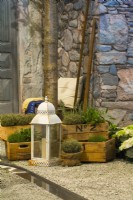 Exposition d'herbes en pots et lanterne devant la maison en pierre de cour italienne contemporaine. Un canal d'eau qui coule sur la surface de gravier. 