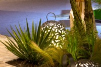 Lampadaires luminescents en laiton parmi Stipa tenuissima et Yucca filamentosa à côté d'une terrasse. Concepteur : Vetschpartner, Berger Gartenbau et Livingdreams. Giardina-Zurich, Suisse. 