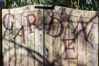Le mot « Jardin », les lettres en acier doux rouillé attachées à la porte d'entrée en bois du jardin Veddw. 
