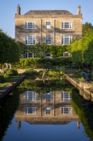 Vue vers Daglingworth House, Gloucestershire, à travers l'étang du jardin formel avec un reflet parfait de la maison 